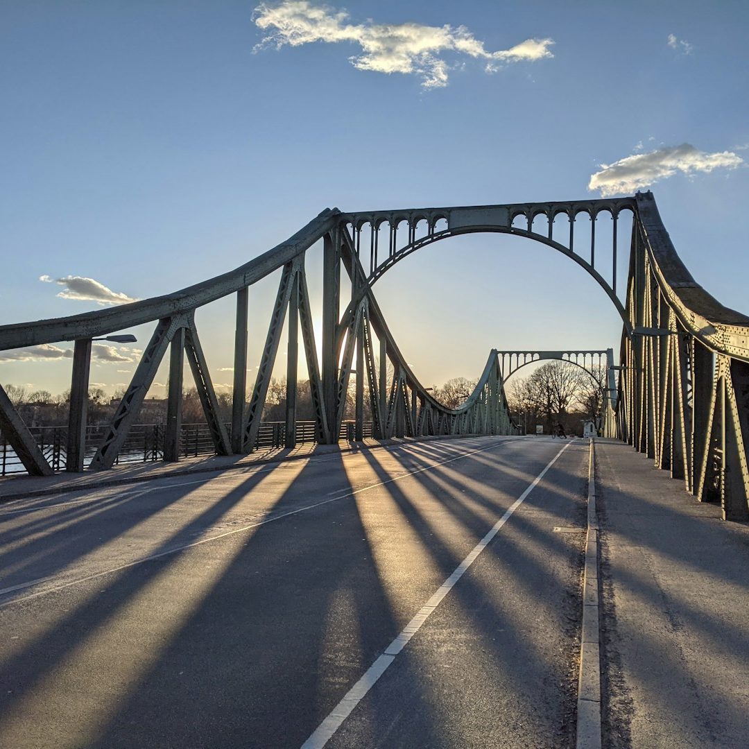 Die Glienicker Brücke in Potsdam mit Bögen und langen Schatten bei Sonnenuntergang.